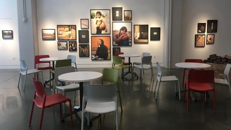 Photo of an art gallery with large photographs hung on the walls and cafe tables