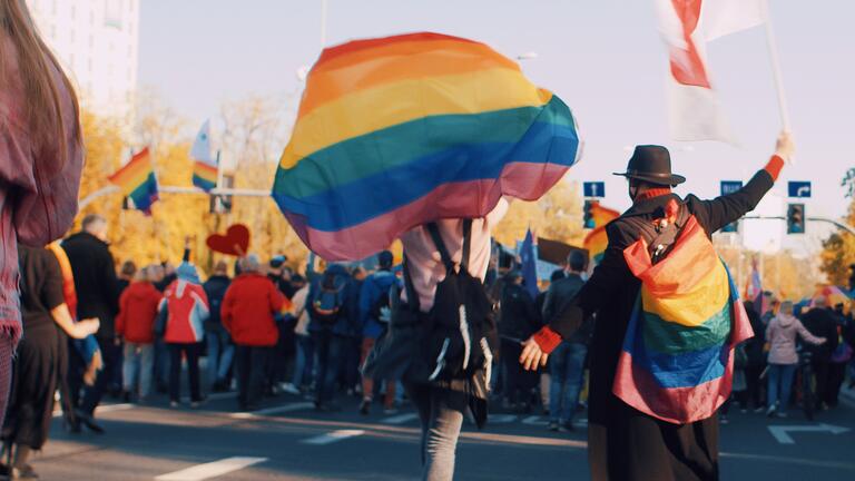 Two people walking in a pride parade holding flags