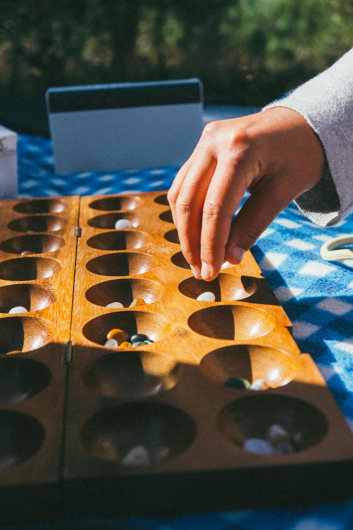 Hand hovering over a mancala board