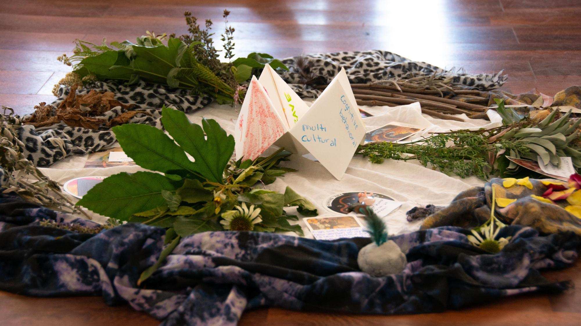 Photo of a circle of leaves, stones, and papers on a wood floor
