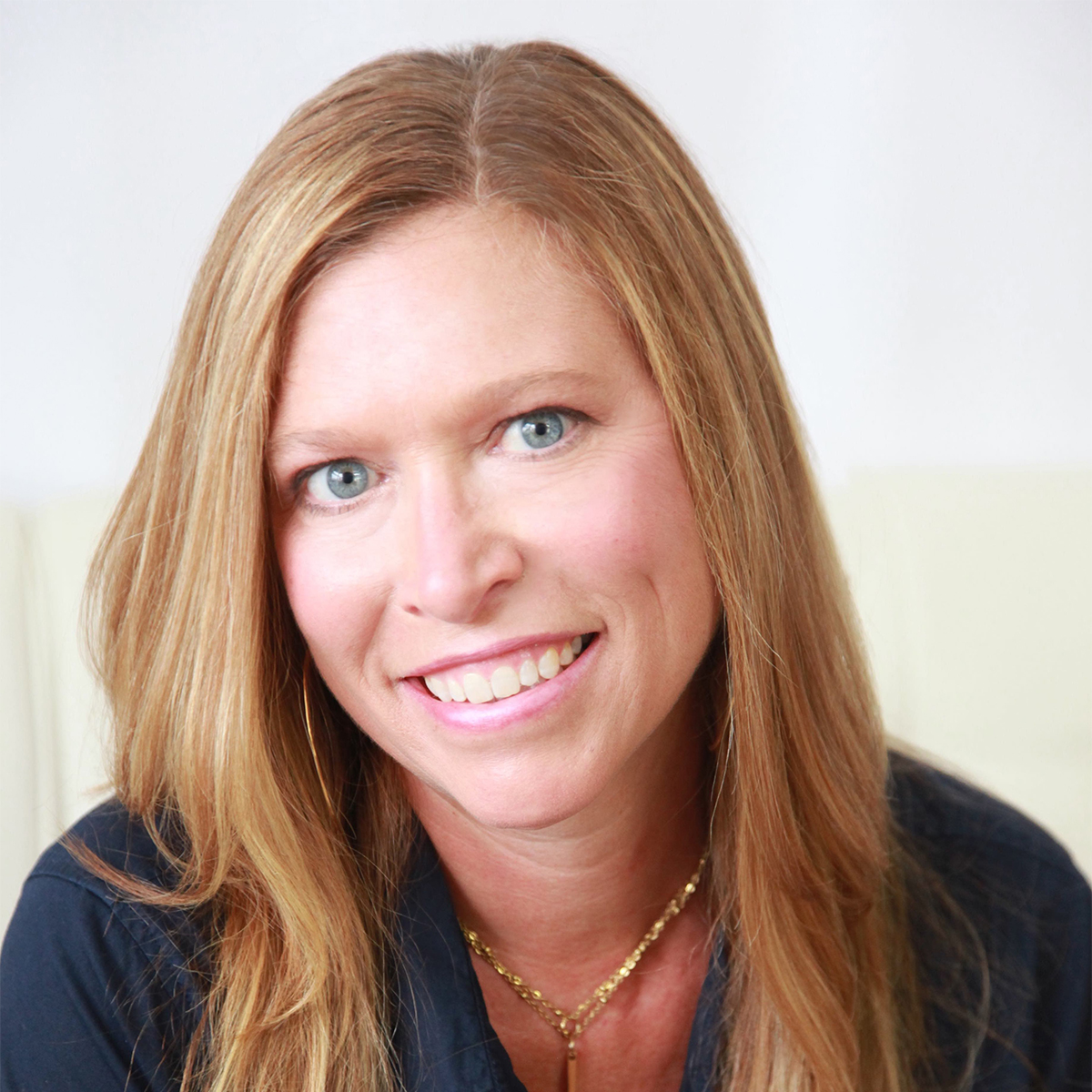 Christine Brooks color portrait. Christine is a white woman with strawberry blond hair that goes past her shoulders. She is smiling and posed in front of a beige background.