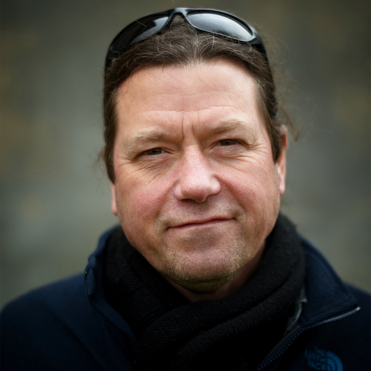 James Canton color portrait. James is a white man with dark brown hair pulled back and Black sunglasses on top of his head. He is smiling and wearing a dark-colored coat and scarf.