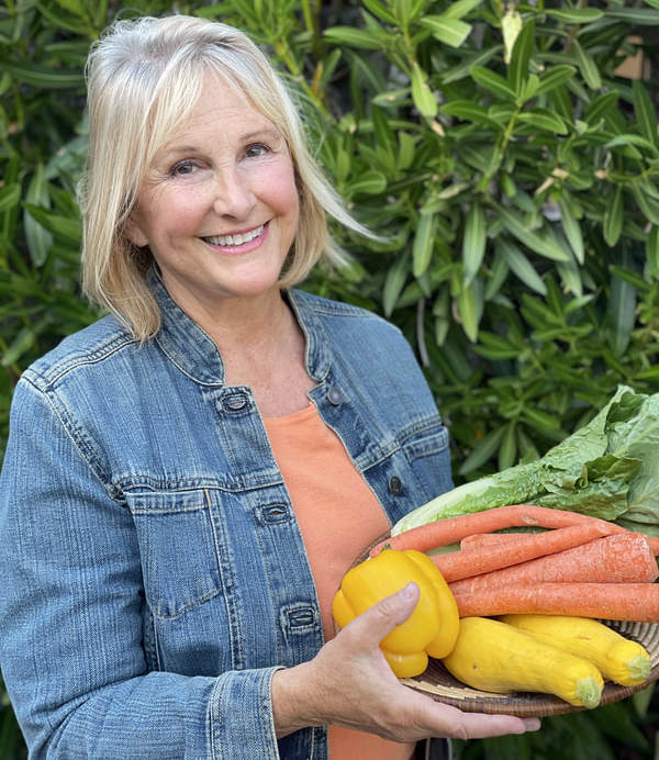 Photo of Meg Jordan holding a woven plate of vegetables.