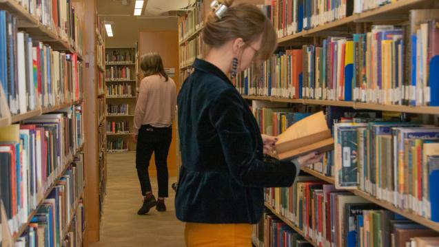 2 students reading in the stacks