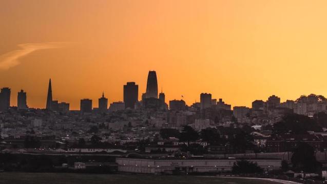 A city skyline with an orange sunset.