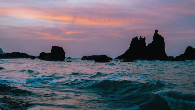 A photo of ocean waves with a rocky beach in the background.