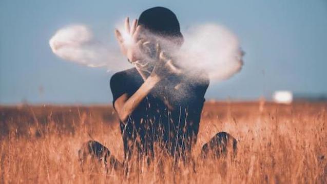 A person in a field throwing white dust in the air. Find out more about the Integrative Health Studies Online Master's Program at CIIS