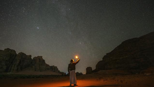 Person holding up light in sky