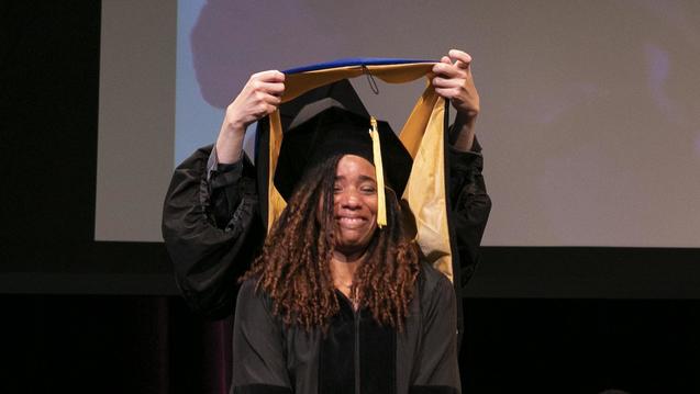 Photo of a woman receiving her Ph.D. hood