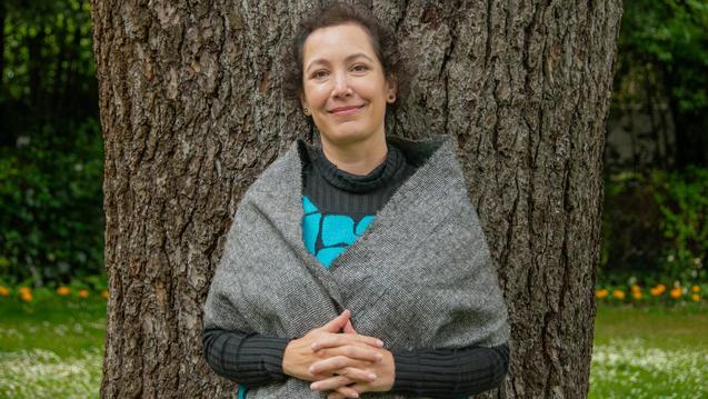 Headshot of Charlotte Saenz standing with tree trunk background