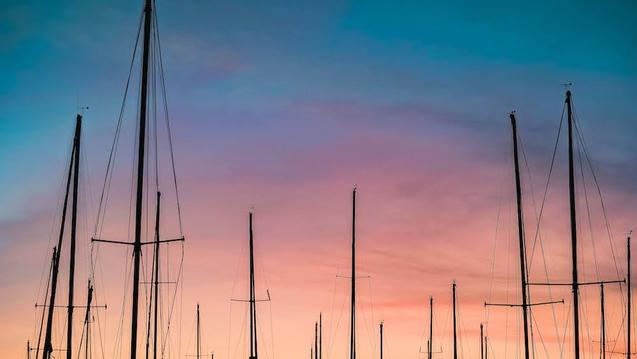 Pink sunset with sailboat poles in foreground.