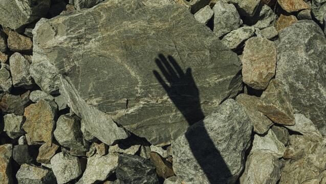 Shadow of a hand on a stone
