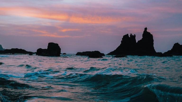 A photo of ocean waves with a rocky beach in the background.