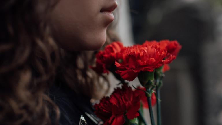 Person holding flowers grieving.