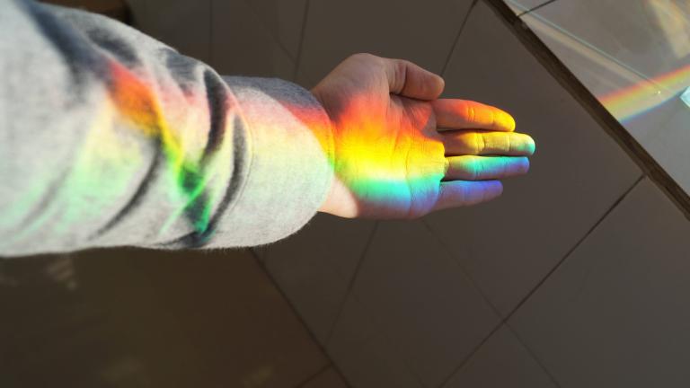 Rainbow light shining on an open hand