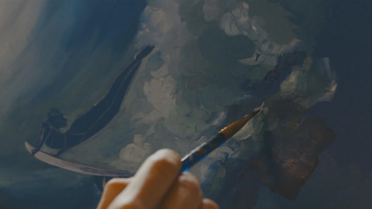 Close up of a hand using a paintbrush to daub white paint onto a canvas. Still from video by Yaroslav Shuraev from Pexels.