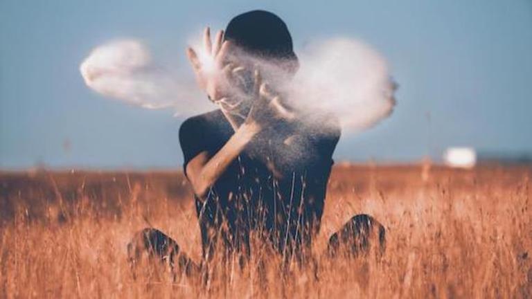 A person in a field throwing white dust in the air. Find out more about the Integrative Health Studies Online Master's Program at CIIS