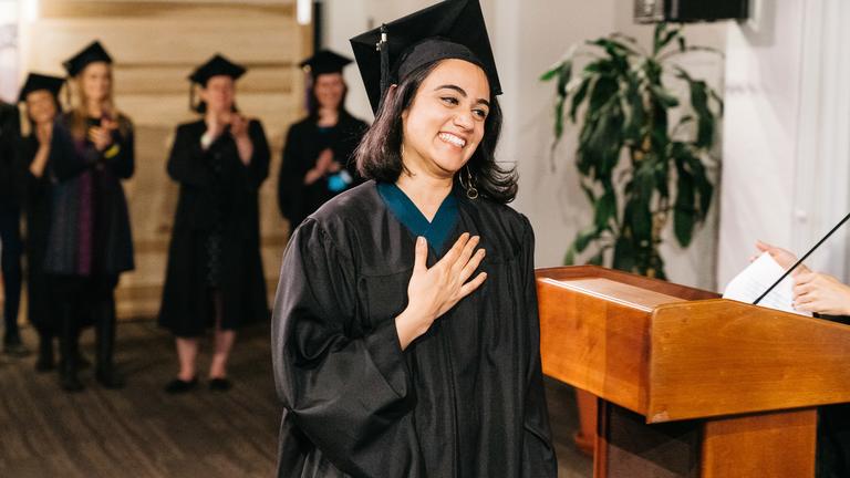 graduate holding heart as accepting degree at graduation