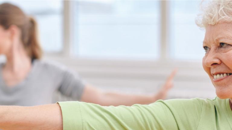 Photo of two people practicing yoga in Warrior 2 pose.