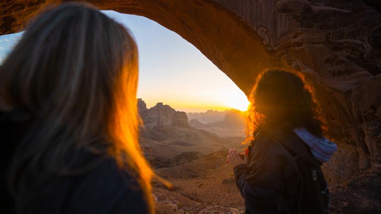 People looking out beyond arch in Hisma desert