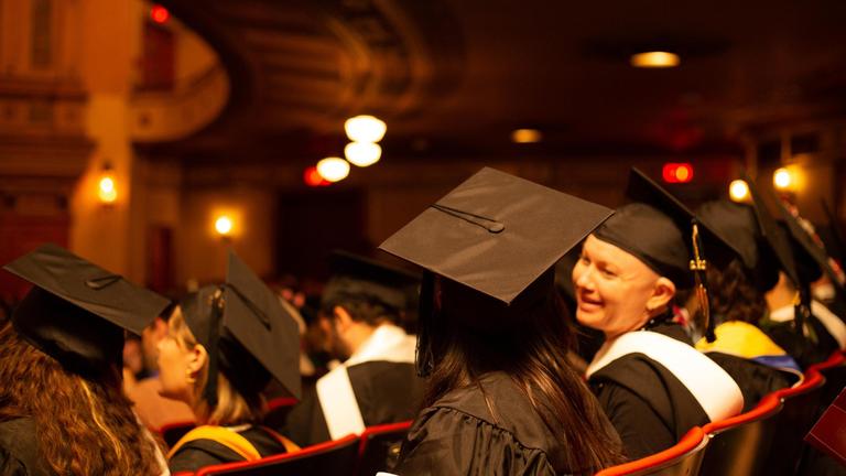 Photo of seated graduating student at commencement