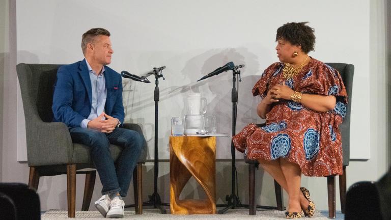 Photo of S. Brock Blomberg and Kathy Littles sitting on a stage with microphones