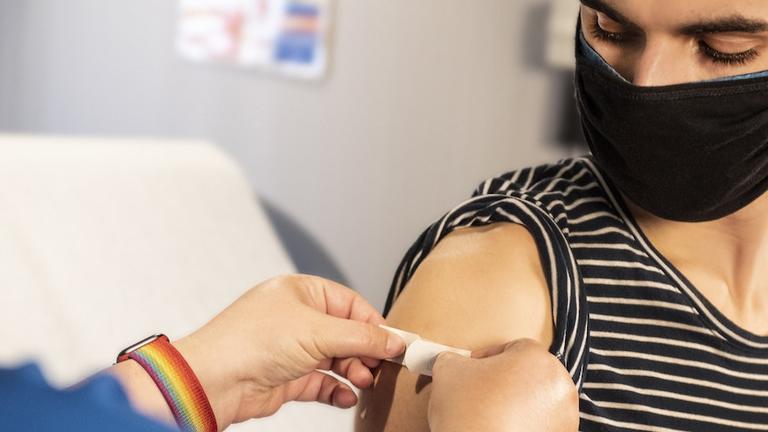 Image of a nurse putting a bandaid on a person's arm after a vaccine. Find out more about the Integrative Health M.A. program at California Institute of Integral Studies (CIIS)
