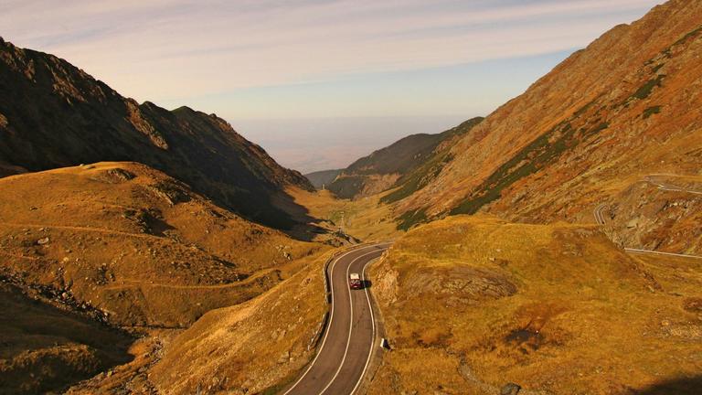 Vehicle on road near hill during daytime