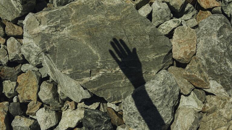 Shadow of a hand on a stone