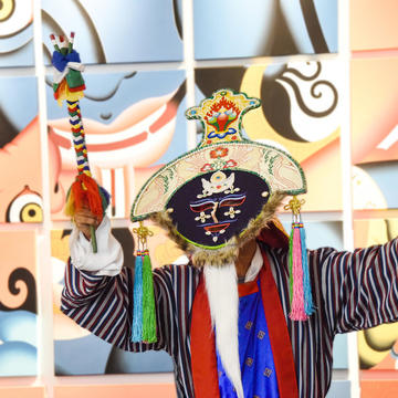 Photo of a dancer in Tibetan clothing holding a colorful wand