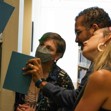 Photo of three people looking at a library bookshelf