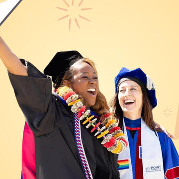 Graduate holding up diploma with professor