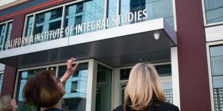 Two CIIS staff members standing in front of CIIS main campus building.