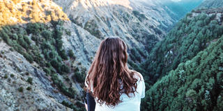 Photo of the back of a person sitting looking over a mountain canyon