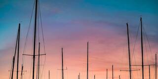 Pink sunset with sailboat poles in foreground.