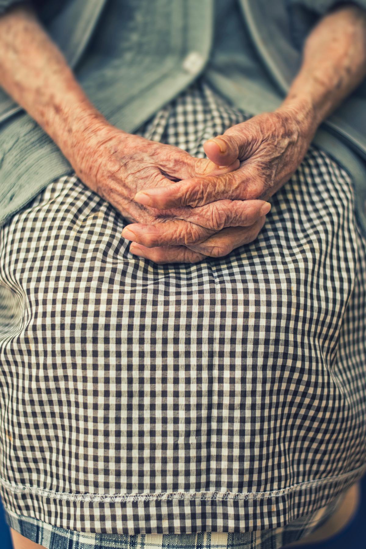 Close up of an elderly person's hands folded on their lap