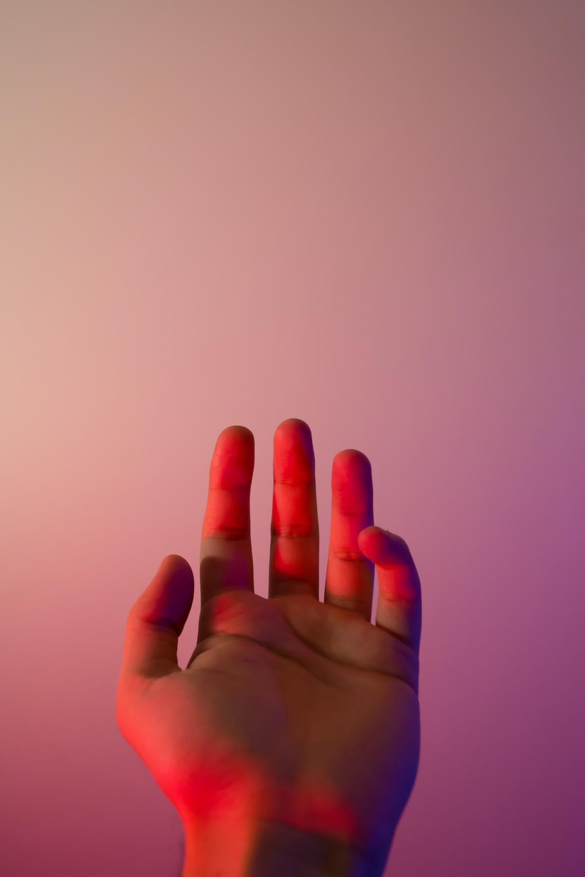 A palm facing upword with red and pink colored light on it and reflecting behind.