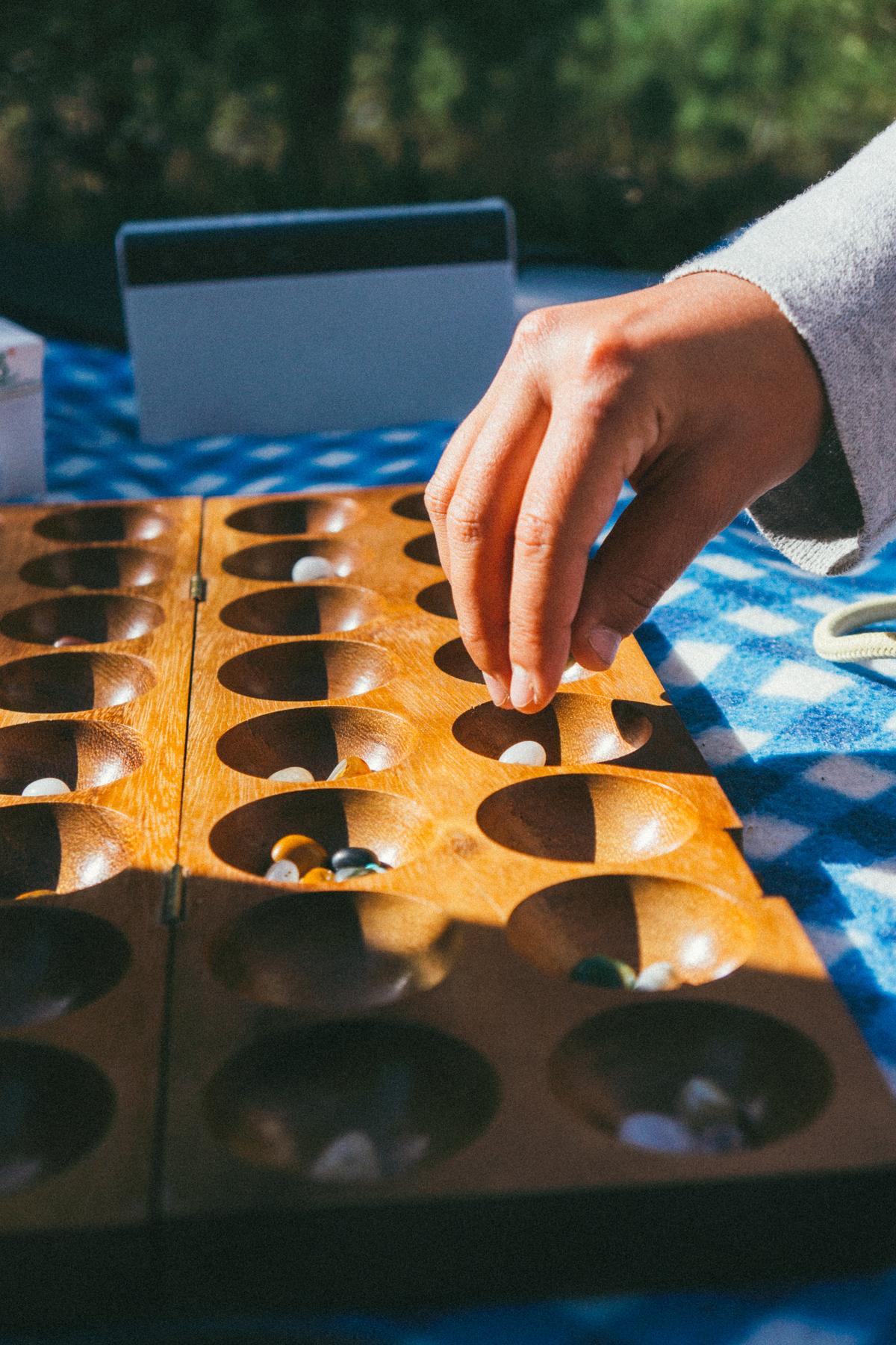 Hand hovering over a mancala board