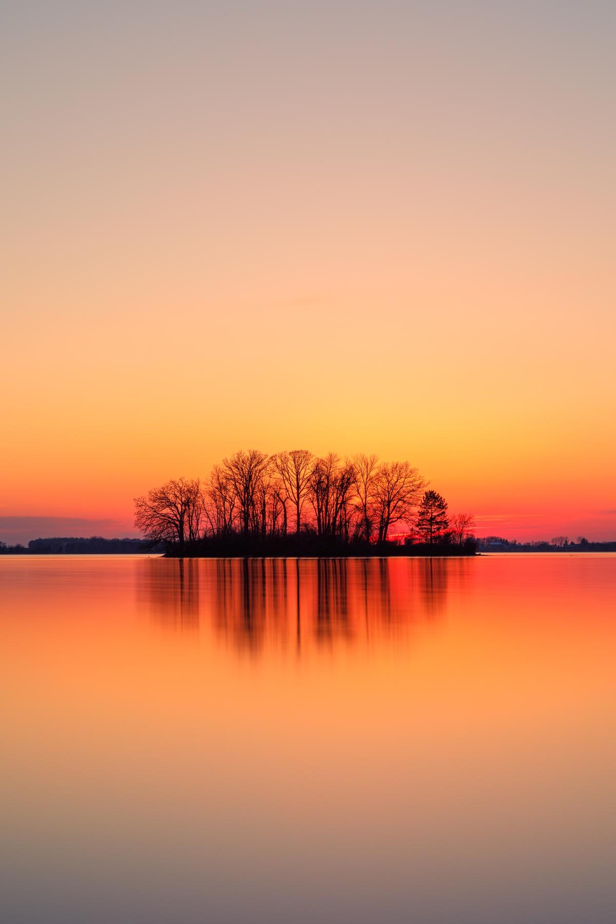 Sunset featuring trees and water