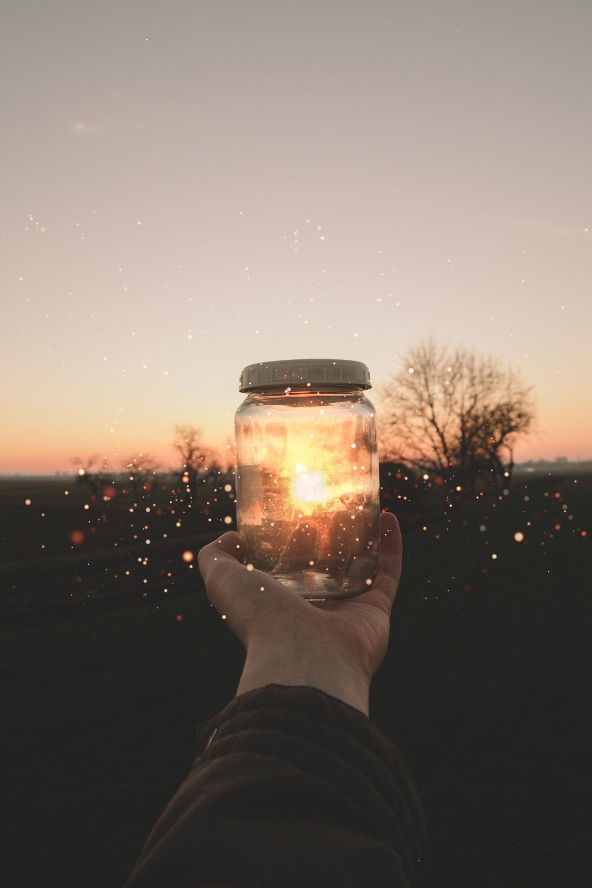 Hand holding a jar full of sparkling light