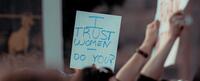 People protesting holding a sign saying "I trust women, do you?"