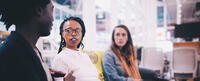 Group of three young professionals sit together on a couch the two on the right are looking at the one on the left. Learn about how to finish your Bachelor degree at CIIS.