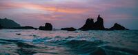 A photo of ocean waves with a rocky beach in the background.