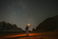 Person holding up light in sky