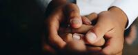 Hands of a person of color holding a woman's hands to symbolize equity and inclusion in integrated health at CIIS