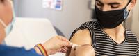 Image of a nurse putting a bandaid on a person's arm after a vaccine. Find out more about the Integrative Health M.A. program at California Institute of Integral Studies (CIIS)