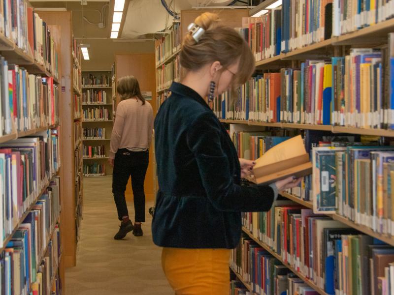 2 students reading in the stacks