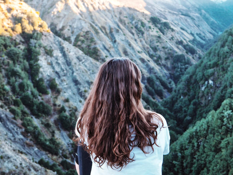 Photo of the back of a person sitting looking over a mountain canyon
