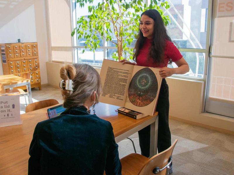 Photo of a woman showing a book in the library