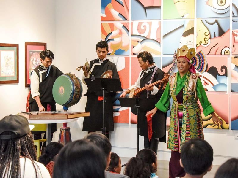 Photo of four musician of Tibetan music performing in an art gallery to a crowd